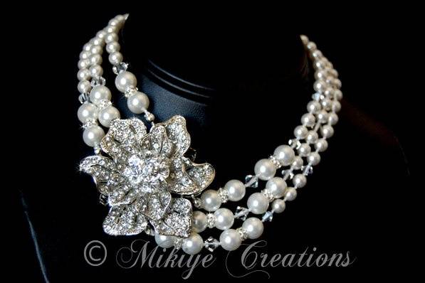 Vivacious Vivienne
This stunning one of a kind original Mikiye Creations is an amazing accessory. Designed to be worn close to the neck this elegant statement piece was inspired by my love for Old Hollywood glamour. I still LOVE to watch movies from the 30's and 40's! Individually hand strung and knotted white Swarovski pearls create this heirloom quality piece. Hand knotted pearls prevent the pearls from rubbing together and being scratched. This keeps your pearls looking beautiful for years to come. It is understood in the industry that all the top quality jewelers hand string and knot their pearl necklaces.
Three lovely strands of opalescent white Swarovski pearls gleam and glow holding a vintage inspired rhodium plated rhinestone brooch. various sizes of clear Swarovski crystals and rondells are sprinkled in adding more luxurious shine. I tried to take clear photos to show off how pretty this necklace is.
Ultra glamourous.
This is a perfect piece for a stylish and sophisticated Bride as well as would make an amazing piece to wear to any special occasion!
Three strand sterling silver adjustable hook clasp closure.
Necklace approximately 13 inches (inside strand) with a 1.5 inch extender for adjusting size.
Don't settle for an imitation.
A TRUE and ORIGINAL Mikiye Creation.