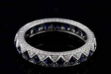 Diamond and Sapphire Art Deco Style Platinum Eternity Wedding Band 3.8 mm Widehttp://www.orospot.com/product/b198168mh/diamond-and-sapphire-art-deco-style-platinum-eternity-wedding-band-3-8-mm-wide.aspxSKU: B198168MH $1,899.00This stylish art deco inspired platinum wedding ring contains 22 French cut blue sapphires (Approx. 1Cttw) set in milgrained bezels and 44 micro pave set round brilliant diamonds (G color and VS clarity approx. 1/3Cttw). This band is 3.8 mm wide and 2.3mm tall. Sides have detailed design and top edges are milgrained. This band is available in all sizes. Please allow 2- 3 weeks to complete the order.