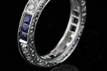 This gorgeous ,art deco design, platinum eternity band contains 12 French cut natural blue sapphires (Princess cut - approx. 1cttw) channel set and 12 round brilliant diamonds pave set (G-H color and VS clarity, approx. .35Cttw). This vintage inspired eternity ring is 3.6mm wide and approx 2mm tall. It is hand set, edges are milgrained and sides are engraved. Also available with rubies and diamonds (please contact us for more information). Please allow 2- 3 weeks to complete this order.