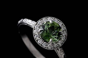Diamond Round Green Tourmaline Engraved Vintage Halo Style Engagement Ringhttp://www.orospot.com/product/r1071ven/diamond-round-green-tourmaline-engraved-vintage-halo-style-engagement-ring.aspxSKU: R1071VEN $569.00This beautiful halo engagement ring is made of 14k white gold. Ring contains round cut, green tourmaline center stone (6mm, approx 1ct.) and small diamonds, (.16cttw, G-SI1 quality) prong set all around. Engraved shank is 1.8mm wide and 1.4mm tall. Vintage style ring is available in all sizes, please contact us for more information. This style is also available in a variety of other gems such as: Citrine, Blue Topaz, Amethyst, Garnet and Peridot. Please contact us if you are interested in any of these options. Please allow 2-3 weeks to complete the order.