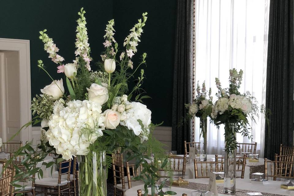 Tall and low centerpieces with white hydrangea, blush roses, babies breath, larkspur and greens.