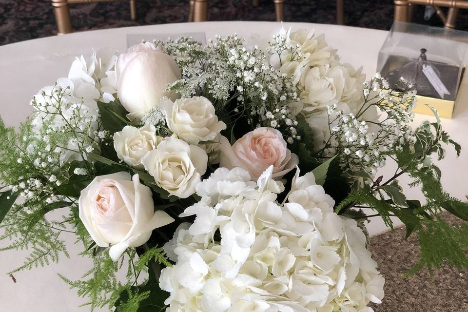 Low centerpiece with white hydrangea, blush roses, babies breath, larkspur and greens.