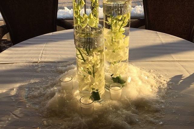 Staggered heights cylinder vases filled with white callas , snap dragons , and dendrobium orchids .