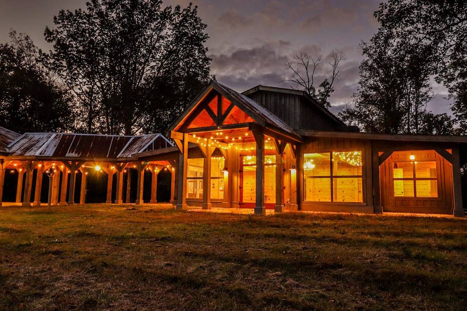 The barn all lit up at dusk