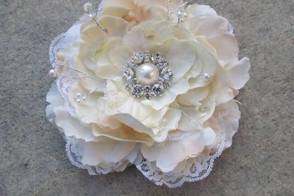 Large ivory peoni with white curled goose feathers..a vintage center with gold filigree and colored pearls is the centerpiece.