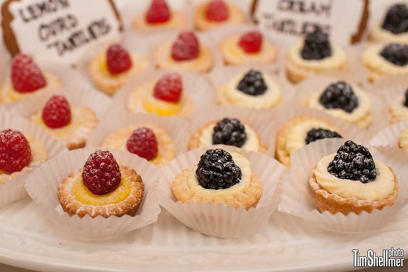 Vanilla pastry cream and lemon curd tartlets, garnished with fresh berries.