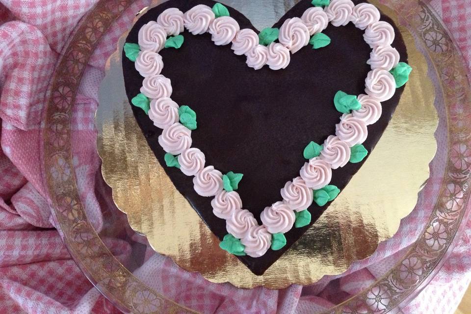 Dark chocolate heart-shaped espresso brownie with strawberry buttercream rosettes.