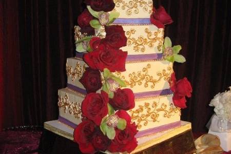 Cake is covered in fondant with fondant draping down each tier. Cake has clusters of sugar roses and hydrangeas