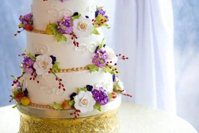 Cake is covered in sugar flowers with hand painted detail