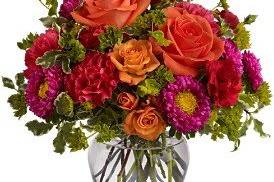 A colorful summer mix of orange roses, asters and buplureum.Nice table centerpiece.