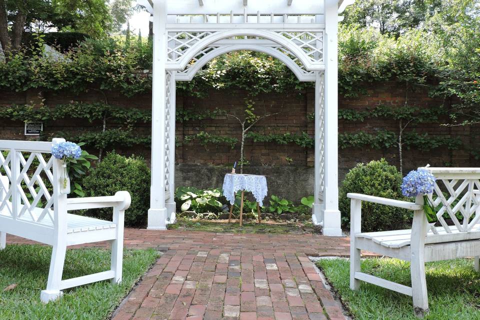 The pergola and garden benches are set up for a wedding ceremony in the verdant orchard of the Burgwin-Wright House.