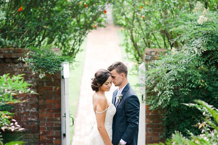 A tender moment between newlyweds surrounded by the beauty of the Burgwin-Wright House gardens.