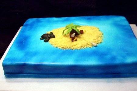 This is a island themed cake and includes marzipan models of a monkey, turtle, palm tree, coconuts and a message in a bottle. The cake itself is a yellow cake that is covered in airbrushed fondant and the island is made out of cake crumbs.