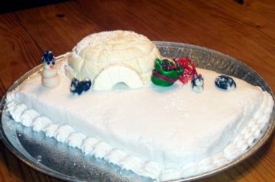 This cake is an example of a buttercream layer cake with a landscape approach instead of the more common tiered style. The animals, igloo, sled and presents are created from modeled marzipan that has been colored using food coloring. The igloo is made from 100% white chocolate and is filled with raspberry milk chocolate ganache resulting in a flavor one might expect from a gourmet white chocolate truffle.