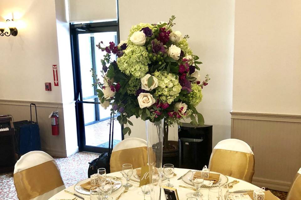 Tall centerpiece including roses, kale, stock, lizianthus, hypericum berries and triclinium