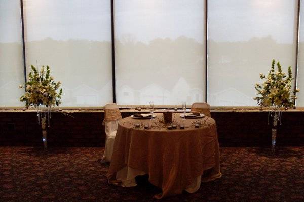 Sweetheart table flanked by two 5-foot high lit arrangements.