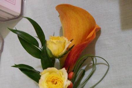 Mother of the bride corsage. 'Mango' call and yellow spray roses with ruscus and bear grass.