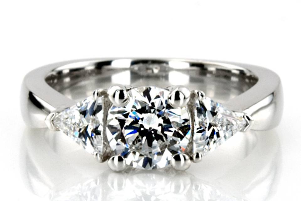 Charming! This gorgeous three stone diamond engagement ring is prong set with 2 trillion cut diamonds totaling 0.70 ct.tw. The diamond ring features a 1.00 ct.tw round cut diamond in the center. This diamond engagement ring is available in white gold, yellow gold, platinum or palladium.