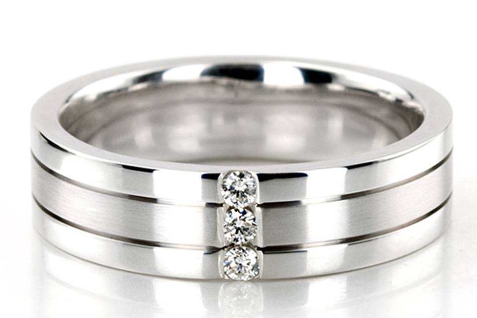 A classic beauty, this 6mm wide Diamond wedding ring has a channel setting. The ring is set with 3 round cut diamonds going across the center of the ring. Each diamond weighs 0.03ct, which is a total of 0.09ct. The diamonds are graded G in color and SI1 in clarity. Center of the band is satin finished, with thin bright cuts on each side. Each side of the band is high polished.