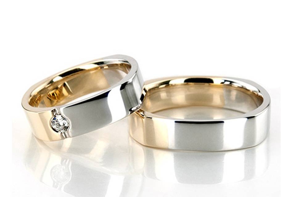 HH-115A Four-sided Two-tone his & hers set. His ring is 5mm wide. Her ring is 5mm wide and set with 1 Round Brilliant Cut Diamond. Diamond weighs 0.1ct. The diamond is graded G in color and SI1 in clarity. The band is partially high polished, and partially satin finished.