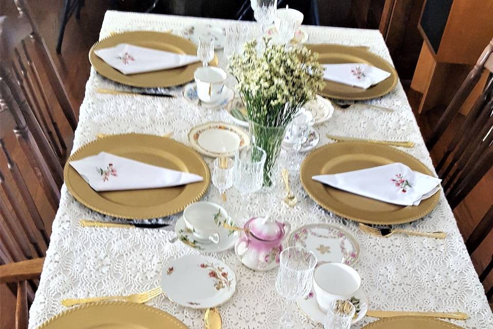 A vintage tea party with crystal stemware, gold chargers and vintage napkins set the mood for a lovely bridal shower.