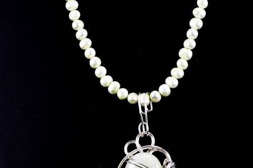 Jade pendant wrapped in swirls of sterling silver and suspended from a strand of matching pearls.