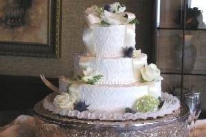 White ribbon cascading down the cake with white roses, white lilies and green hydrangeas on the tiers.