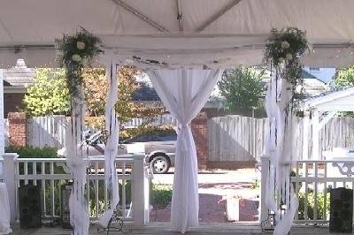 Chuppah with arrangements on the top corners.