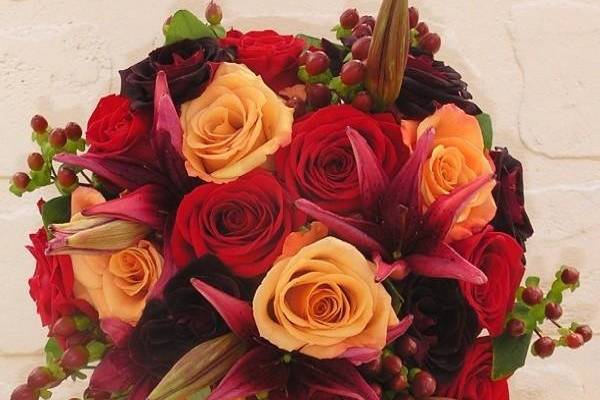 Bride's bouquet with red, burgundy  and orange roses, burgundy lilies and hypericum.