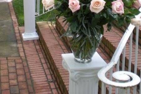 Altar pieces at bottom of stairs consisting of pink roses and curly willow.