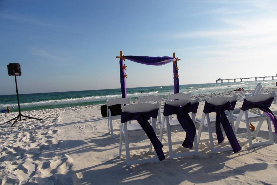 Purple arch set up with chairs and sashes.