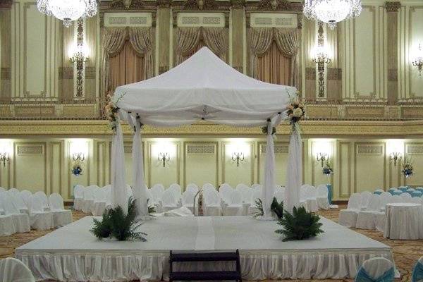 A chuppah set for a wedding at the Palmer House Hilton in Chicago, IL. Flowing organza material covers the chuppa, that is adorn simply with white dendrobium orchids, peach Versilia roses, and ivory hydrangea.