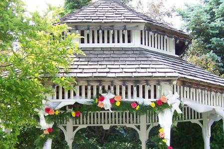 The gazebo at Ruffled Feathers in Lemont, IL.  Green garland with matching spring flowers decorate the opening, while a centerpiece adds color to the interior, and will later be moved to the Head Table in the ballroom.