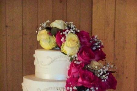 Three tiered fondant cake with whimsical handmade fondant flowers, and rings to complement a fun, happy, unique wedding!