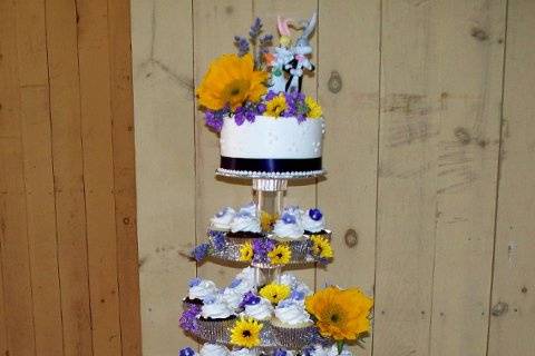 150 Cupcakes with fondant blossoms in varied shades of purple, edible pearl center and gorgeous (real) sunflowers. Cake topper is of Looney Toons characters, as the couple met at Six Flags while working there together.