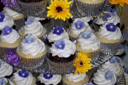 Red Velvet Vegan Cupcakes with Vegan Buttercream and coconut filling.  Coconut cupcakes with vanilla buttercream.  Each cupcake is adorned with a homemade marshmallow fondant purple blossom in a variety of different shades of color, complete with an edible fondant pearl!  Flowers are real and look so cheerful!