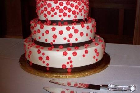 Cascading Coral Flowers:
Coral colored hand-made fondant blooms gracefully cascade down this 4-tiered buttercream cake...complete with chocolate fondant ribbon!