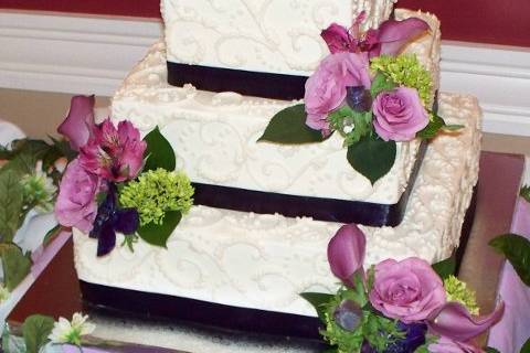 Ivory hand-piped scroll wedding cake in buttercream with fresh flowers.