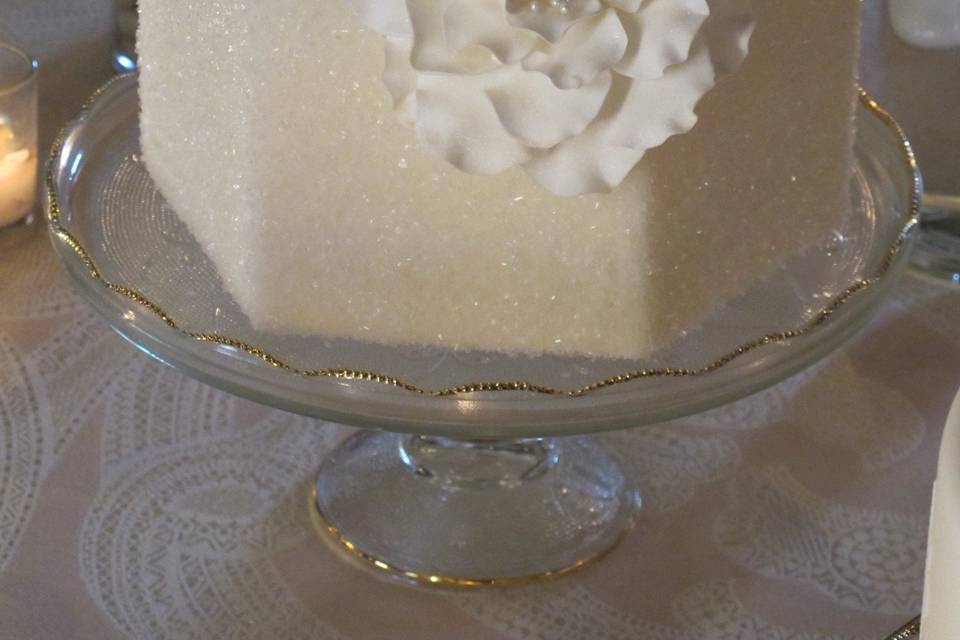 Hexagon tiers covered with sparkly sugar crystals and a handmade, rose-like fantasy flower with pearl stamen center.  Displayed on our vintage Harp Glass stand.