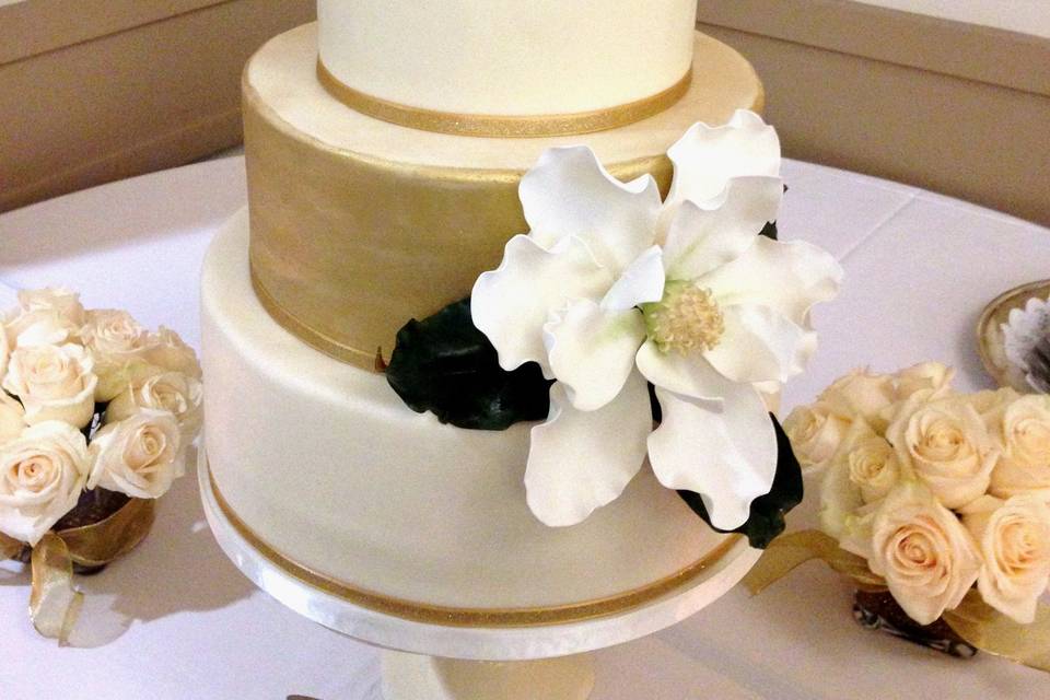 50th Wedding Anniversary Cake by Let's Do Cake!  Covered in fondant with an edible Gold Painted tier and a handmade sugar Magnolia Flower and Leaves.  Purchased topper. 7