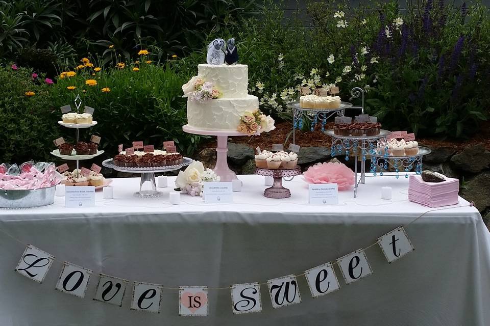 Cake Table by Let's Do Cake with a rustic frosted Wedding Cake with fresh flowers put on by us and assorted mini Cupcakes.  Mice toppers purchased by the bride.