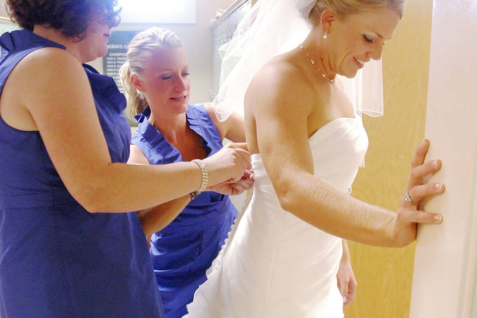 The bride's sisters help her get ready