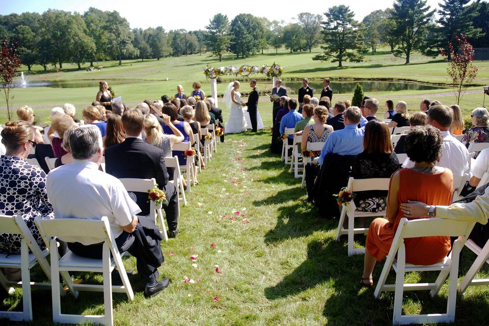 Wide shot of the hot, mid day wedding at a golf course.