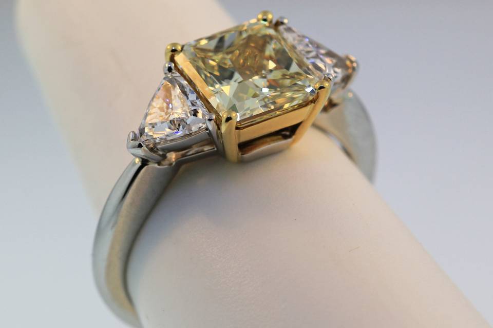 18k yellow gold and platinum diamond engagement ring. Center Diamond is a natural Yellow diamond weighing 2.40cts. The trillian side diamonds weigh .81cts total.  $75,000.00