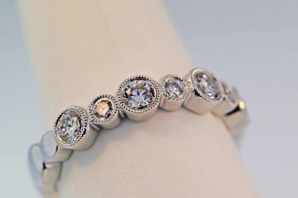 18k white gold diamond wedding band with diamonds half way arround. Each diamond is bezel set with a hand carved milligrain edge .76 carats in diamonds $4,000.00