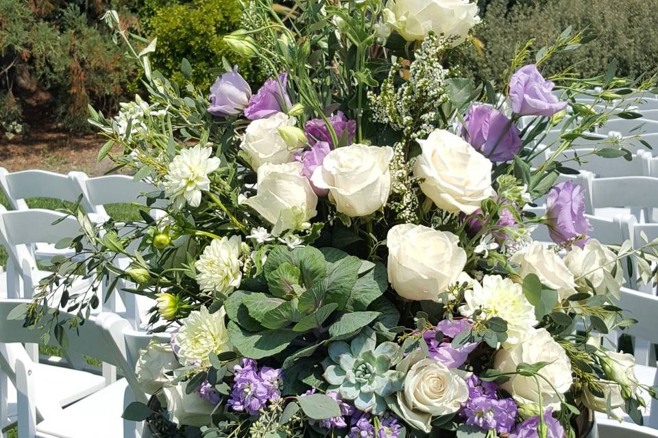 Wine barrel topper flowing with white and lavender flowers and eucalyptus greens