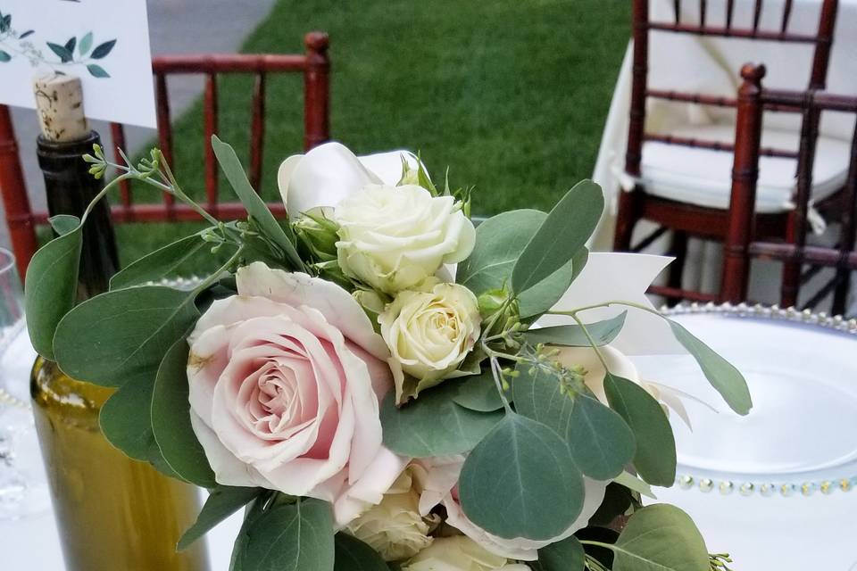 Rustic lantern centerpiece with a bouquet of pink and white roses and eucalyptus greens.