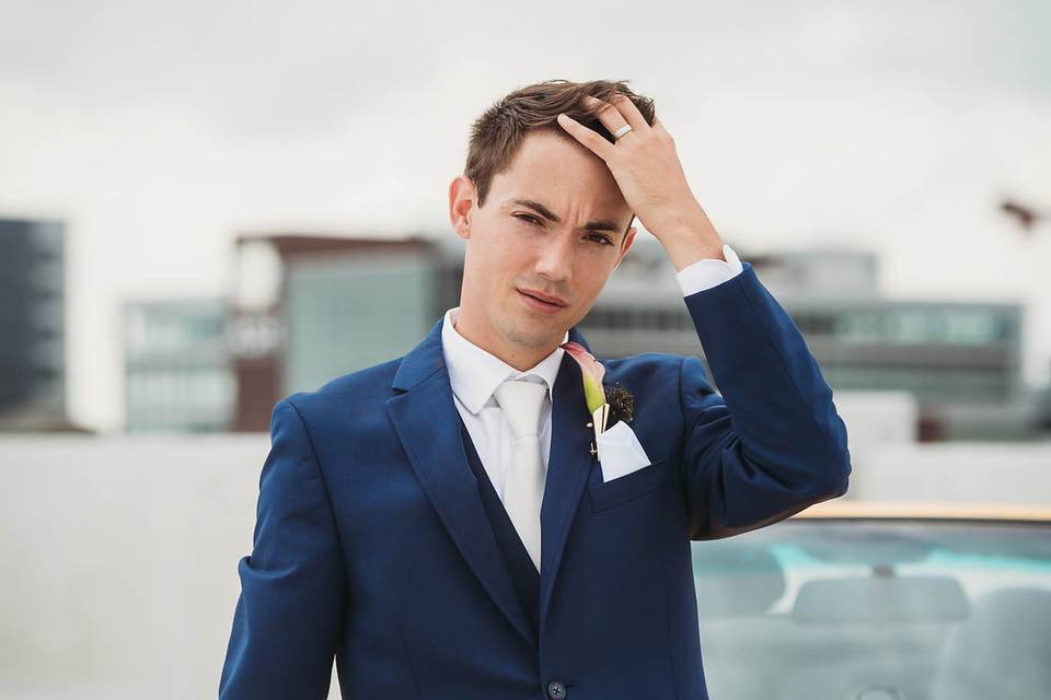 Chic groom posing on rooftop