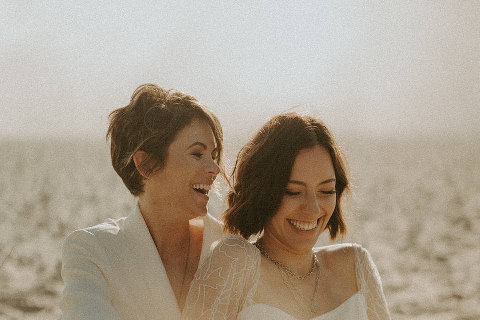 Brides sitting in sand