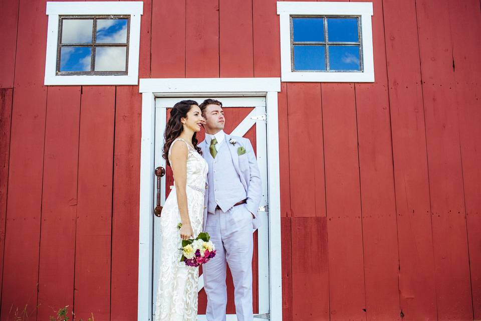 Couple in front of red barn venue